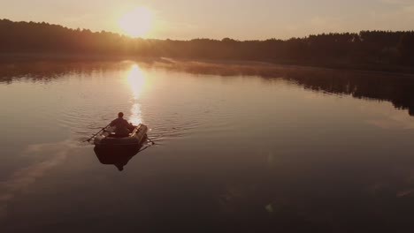 guy paddling an inflatable boat on a quiet lake during a beautiful summer sunset in rogowko, poland