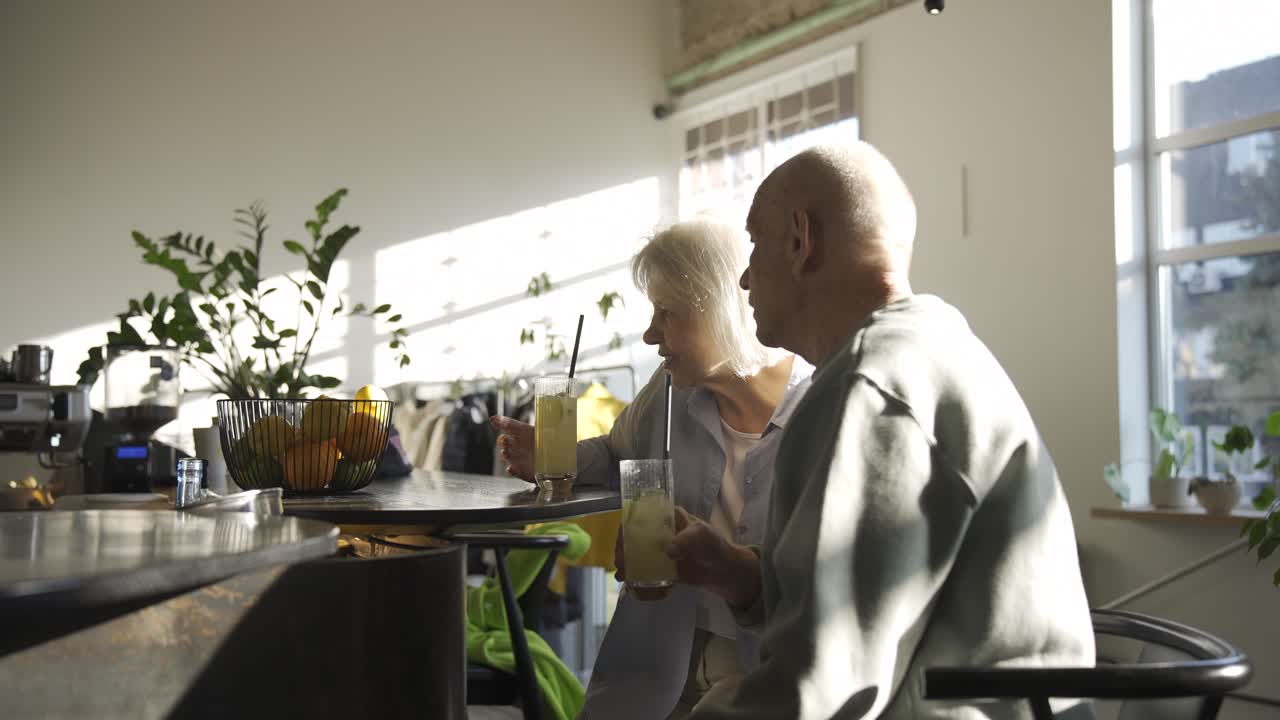 석양에 바에 앉아 있는 동안 리모네이드를 마시고 이야기를 나누는 노부부