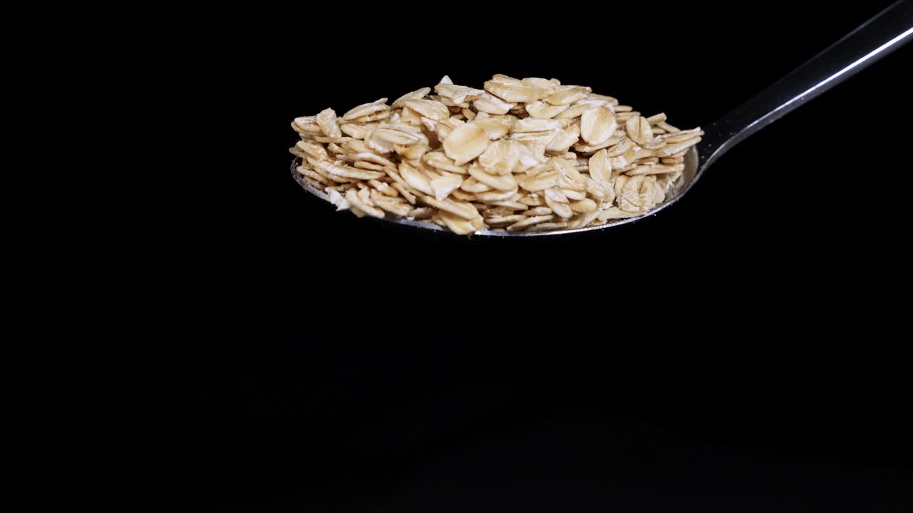 Spoon releases cereal in slow motion, highlighting texture and movement against a dark backdrop