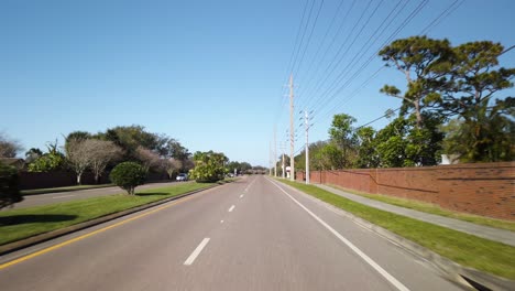 driving on road in residential florida neighborhood on sunny day, pov