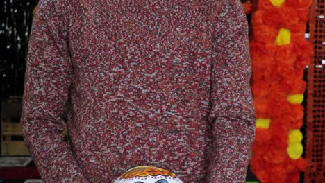 holding decorated skull bucket for mexican day of the dead candy treat