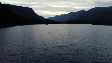 ascending drone shot over a lake with mountains in the background