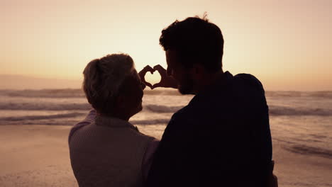 pareja, corazón y silueta de manos en la playa