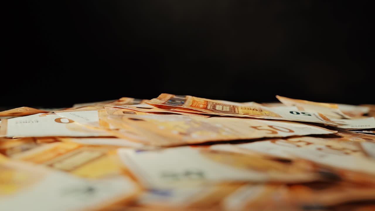 Fallende Scheine, filmreife Zeitlupe auf dunkler Oberfläche, Metapher für Inflationsfinanzierung