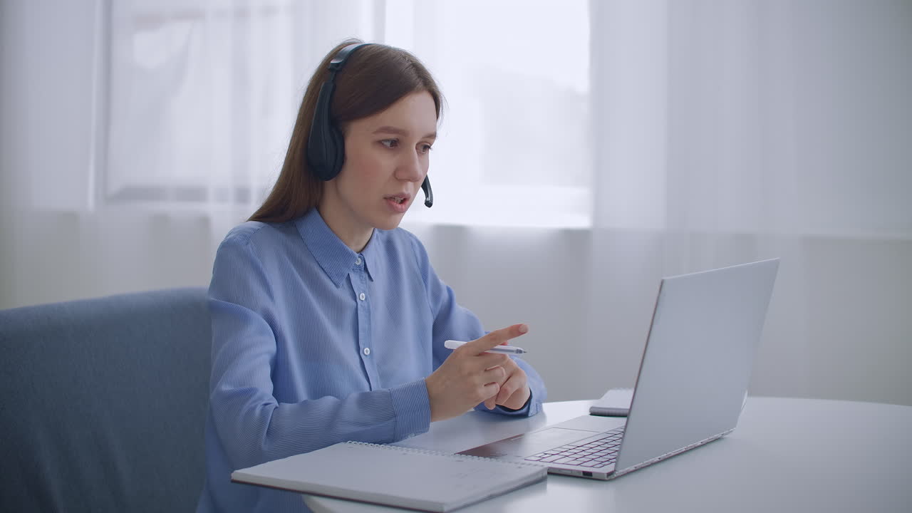 la especialista femenina del centro de llamadas está hablando con auriculares y mirando la pantalla de la computadora portátil en el interior trabajando de forma remota