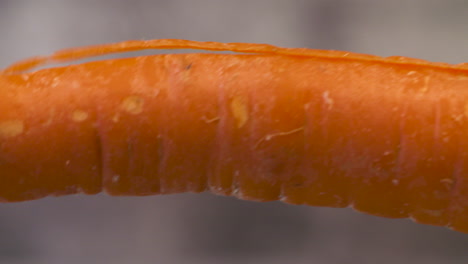 close up of a peeler shaving the skin off a carrot