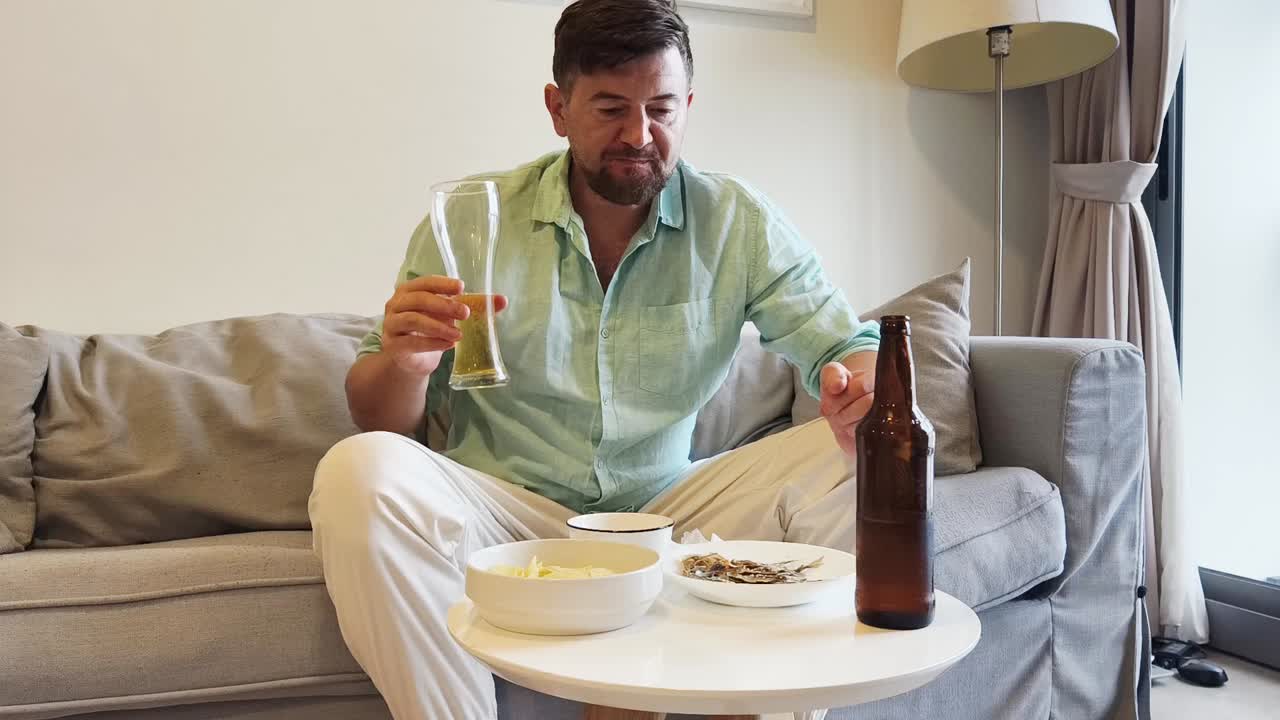 Man relaxing on couch with beer and snacks