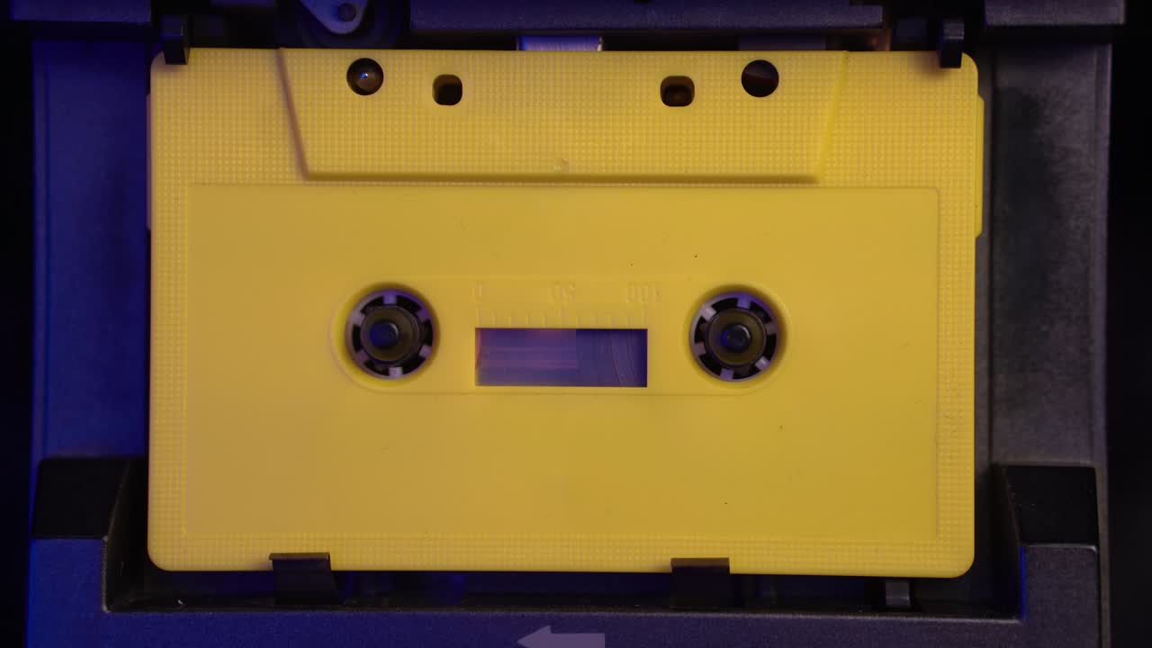 colocación y inicio de la reproducción de la cinta de cassette de audio amarilla, de cerca