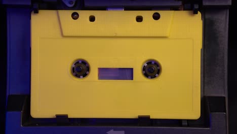 Placing-and-Starting-Playback-of-Yellow-Audio-Cassette-Tape,-Close-Up