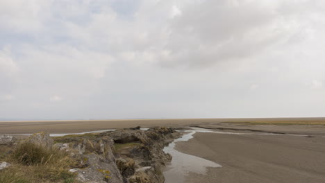 Zeitraffer-Eines-Küstenabschnitts-Bei-Ebbe-Und-Sich-Bewegenden-Wolken