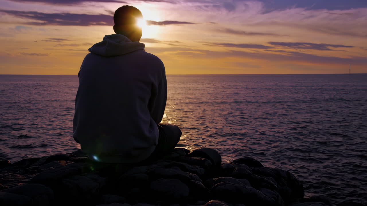 hombre contemplando la puesta de sol sobre el océano