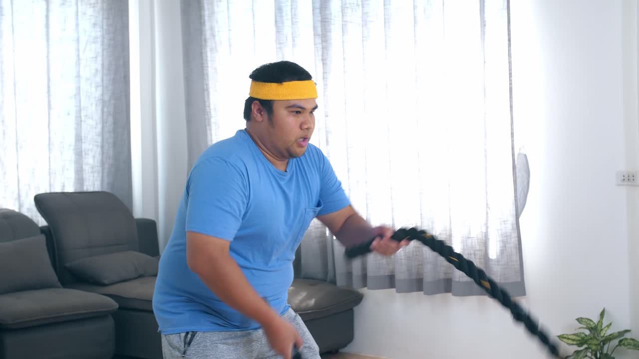 Overweight Man Exercising at Home with Resistance Rope