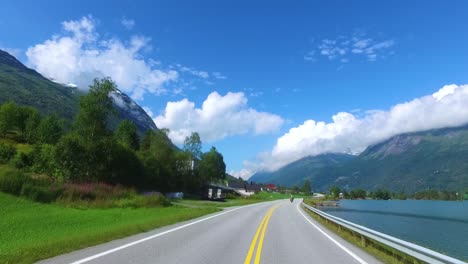 driving a car on a road in norway. in the background, the biker rides a motorcycle.