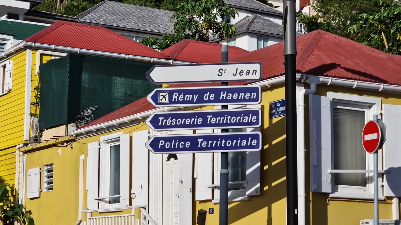 Gadeskilte i Gustavia, Saint Barthélemy-øen, foran et gult hus i et beboelseskvarter.