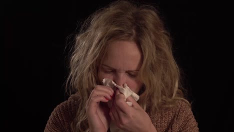 a young european blond women is blowing her nose