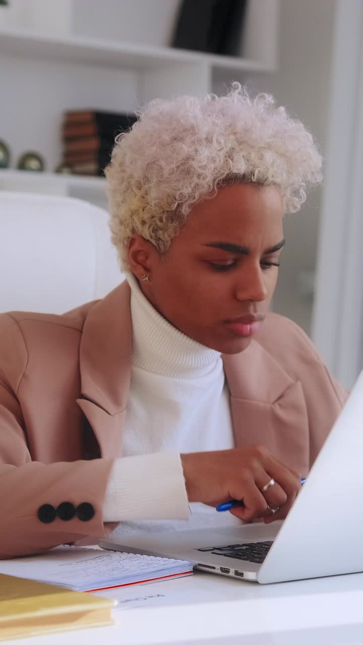 Young professional woman at office desk writes notes and reviews documents