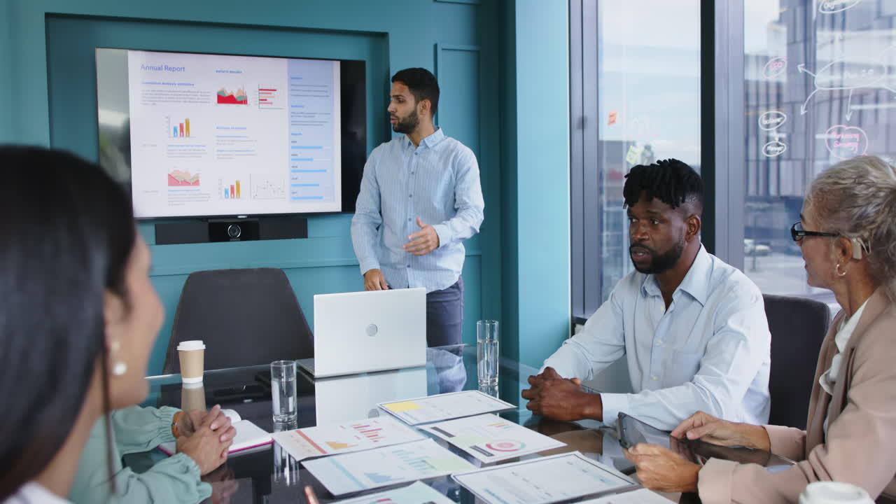 Presenting annual report, businessman pointing at screen in meeting with colleagues