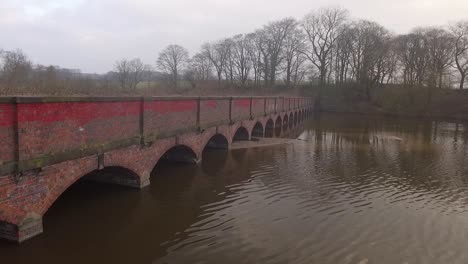 low panning aerial shot across archway bridge over water