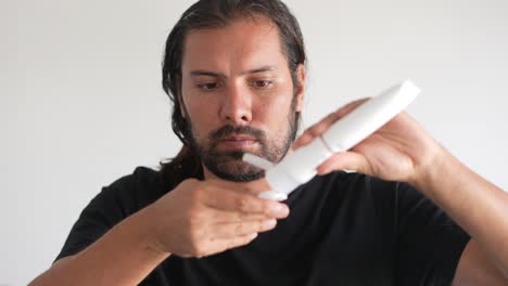 hombre latino cuidando su piel con crema corporal