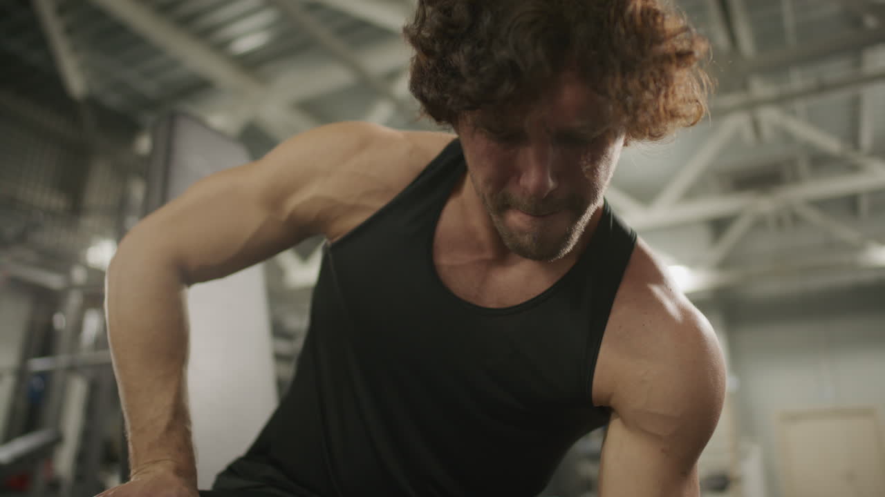 Muscular Athlete Doing Seated One-Arm Dumbbell Curls in Gym