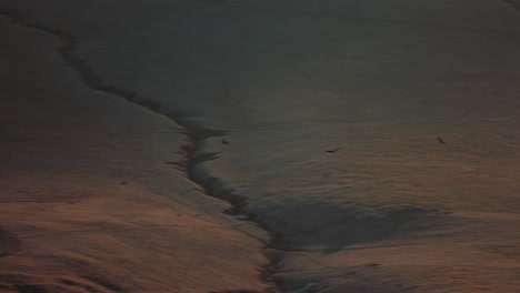camera pans across valley beneath steep mountainous regions at sunset. shot on canon r5 at 4k 120fps with rf 70-200mm f2.8.