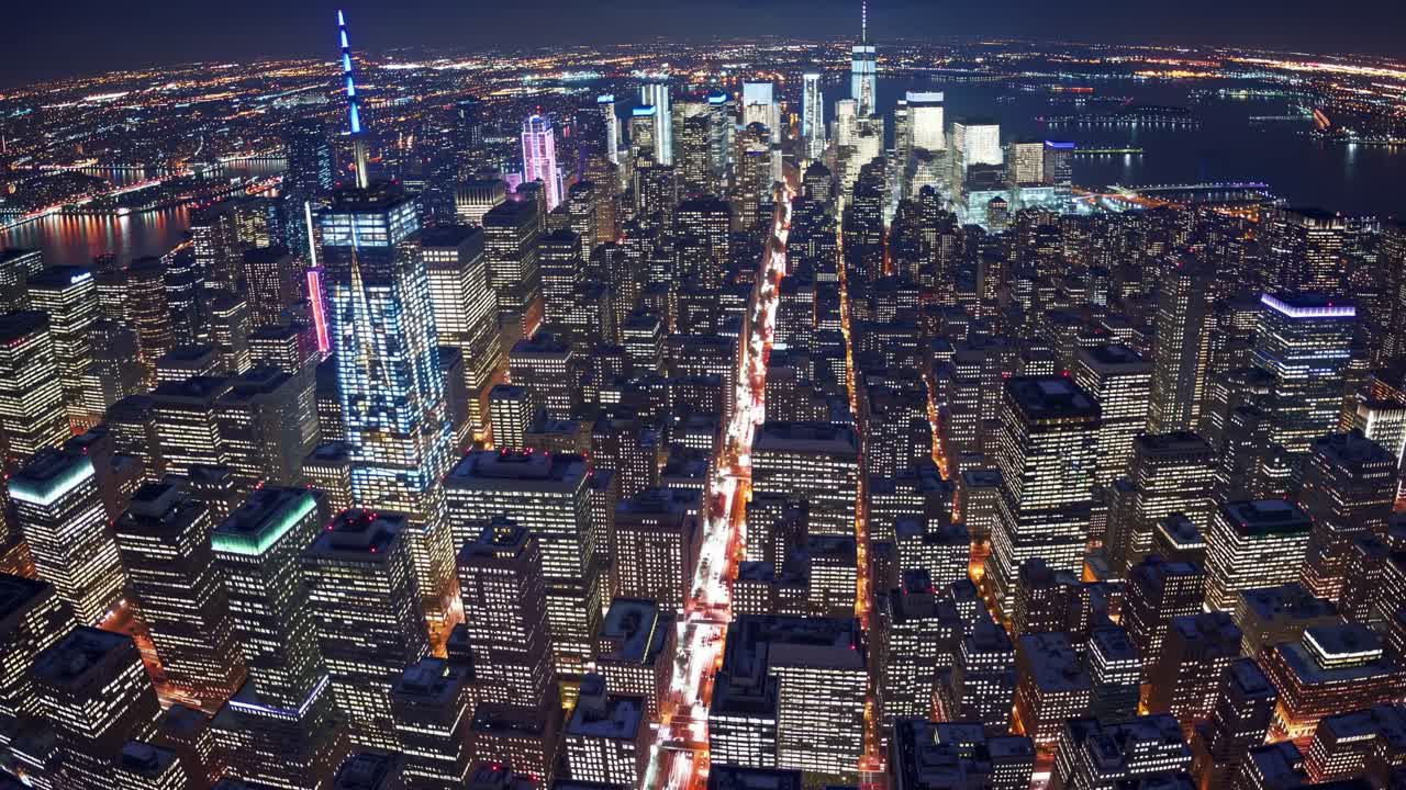 Aerial view of a vibrant city skyline at night, showcasing illuminated skyscrapers and bustling streets, capturing the dynamic energy and urban life in a continuous motion sequence