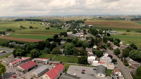 Toma-Aérea-De-Camiones-En-El-Pueblo-De-Intercourse,-Condado-De-Lancaster,-Pa,-Hermosos-Campos-Verdes-En-Verano