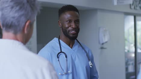 Smiling-african-american-male-doctor-discussing-with-diverse-colleagues-at-a-hospital-staff-meeting