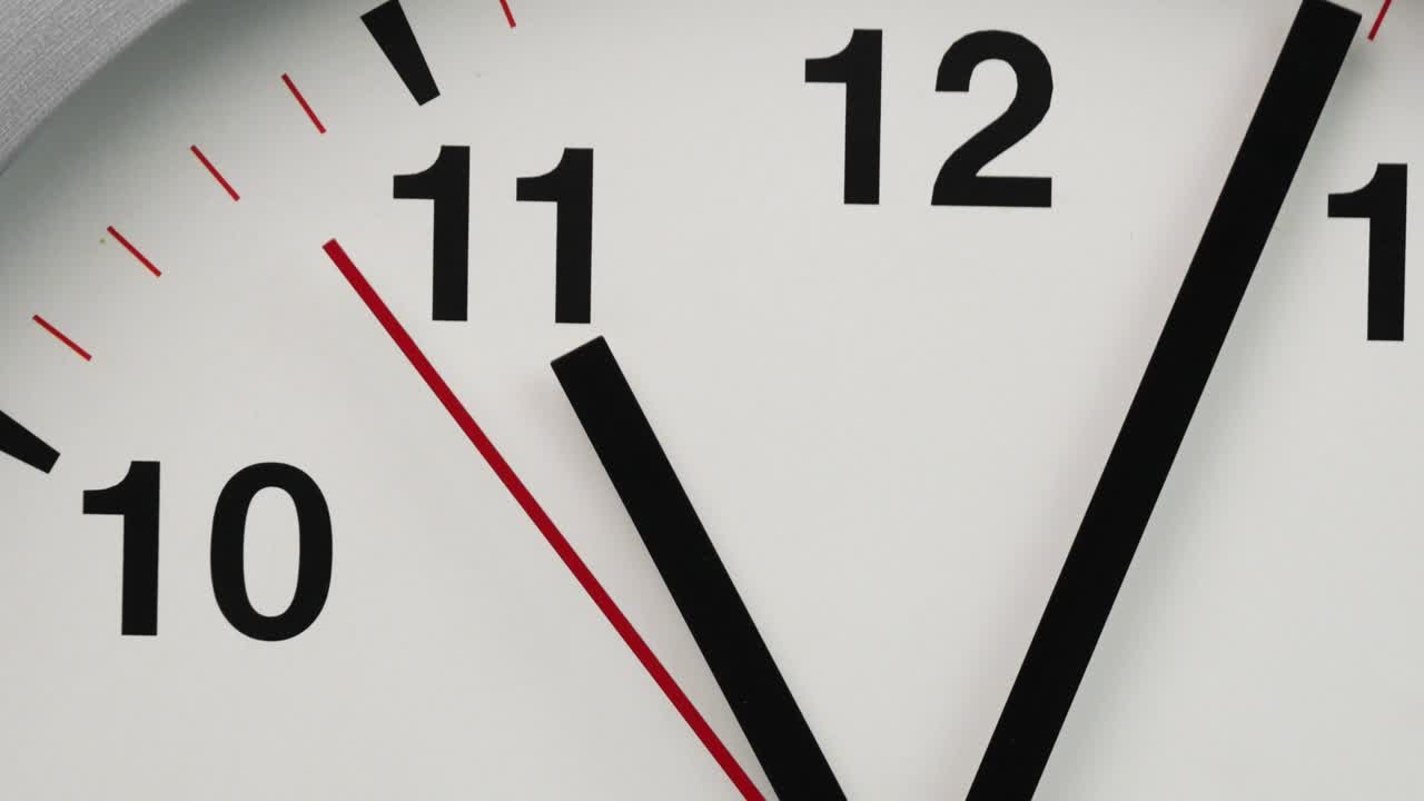 Close-up white wall clock show the time at 11o'clock.