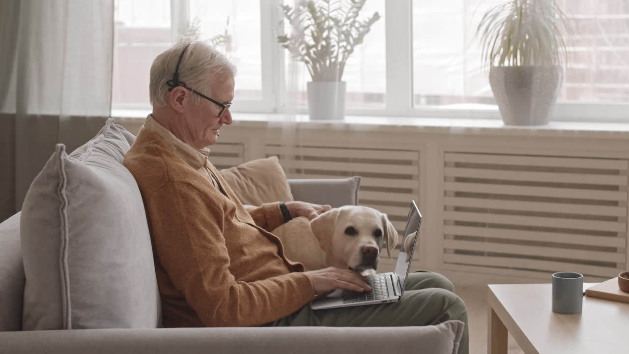Senior Man with Laptop Petting His Cute Dog