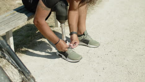 movimiento lento de un hombre con pierna protésica atando cordones en zapatillas de deporte