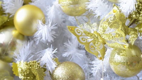detalle de un árbol de navidad blanco adornado con mariposas doradas y objetos