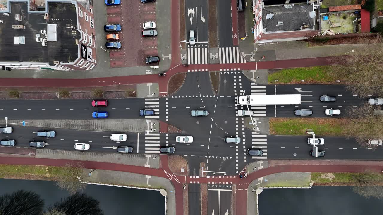 Traffic on junction of dutch city during cloudy day. Aerial top down shot. Truck and cyclist crossing street. Descend shot. Tha hague, Netherlands, Europe.