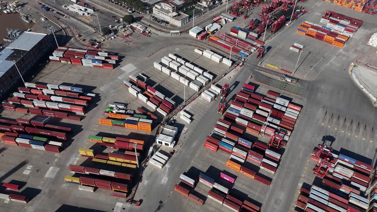 Aerial drone view of Montevideo port’s container yard, with cranes actively moving between colorful shipping containers along the waterfront
