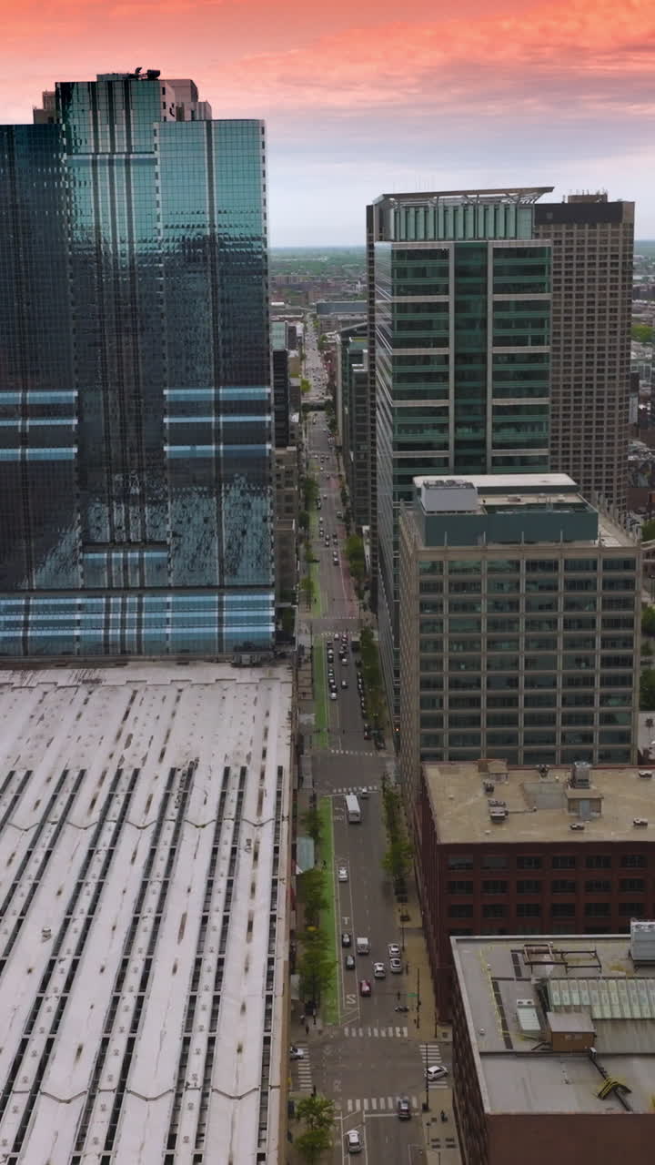 Rows of beautiful modern buildings of stunning Chicago, Illinois. Drone footage over subway depot. Pink sky at backdrop. Vertical video