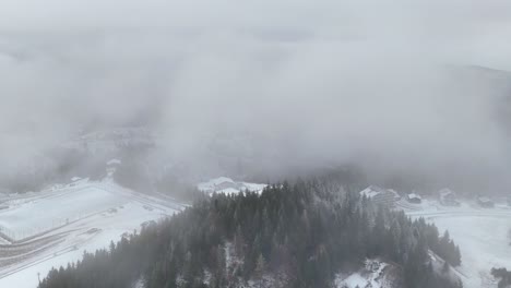 4k aerial drone perspective of winter landscape in carpathian mountains, romania. fir tree forest, snow, fog, mountain peaks with snow. drone going forward passing through the fog. travel destination