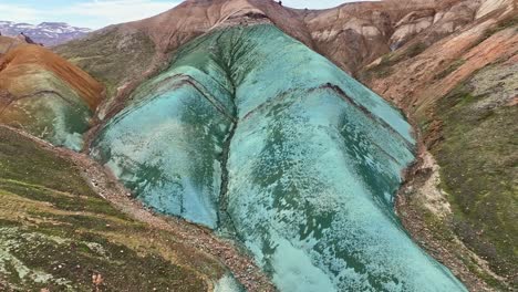 aerial drone low altitude, fixed top-down view with a very slow movement, capturing grænihryggur, the green rock in landmannalaugar, iceland, showcasing medium tones of orange and green