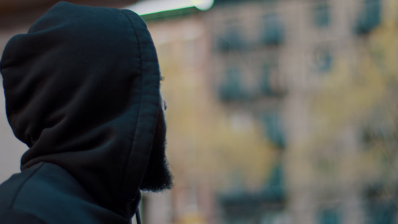 New York, USA, 8 April 2026: Close up of man in hoodie touching forehead outdoors. Side profile of American man wearing hoodie with hand on head in urban setting