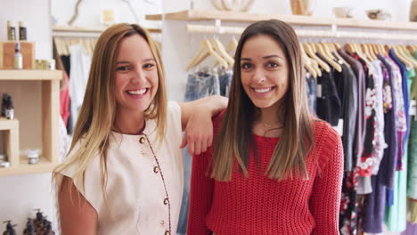 portrait of two female friends having fun shopping in clothes store together