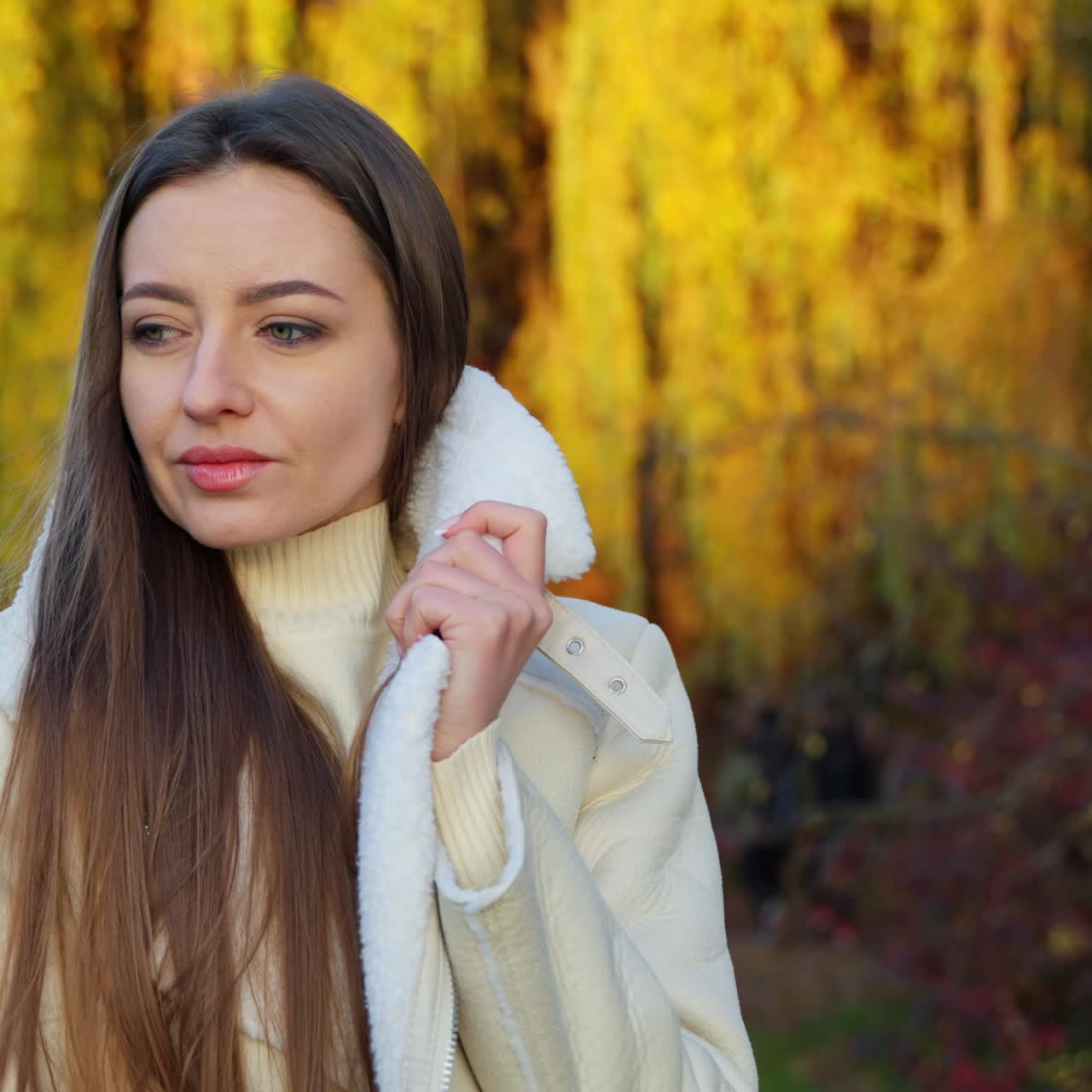 Portrait of young lady in autumn background. Attractive cheerful woman wearing coat