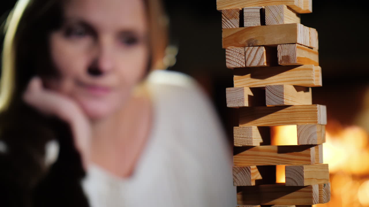 retrato de una mujer jugando un juego de mesa donde necesitas sacar bloques de madera de la torre