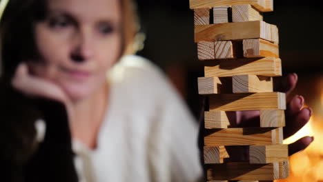 portrait of a woman playing a board game where you need to pull out wooden blocks from the tower