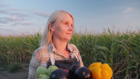 mujer agricultora sosteniendo una canasta de verduras en un campo de maíz al atardecer
