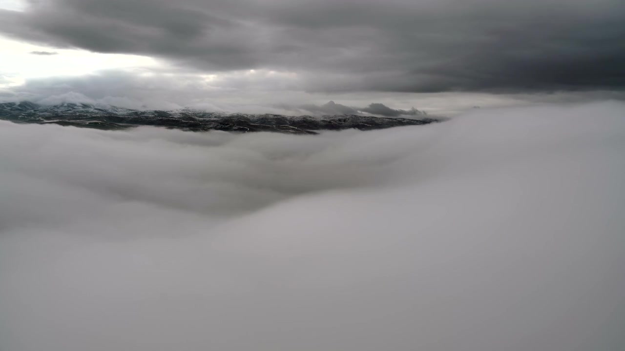 Aerial View of Thick Clouds Over Snowy Mountain Range