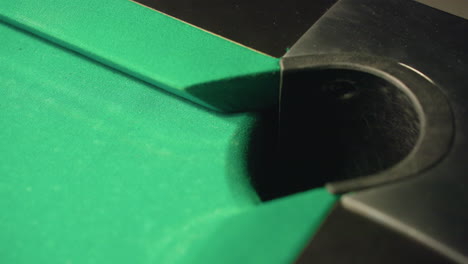 red billiard ball smoothly rolls into pocket of green pool table. close-up shot captures precision, momentum, and final moments of successful shot, highlighting accuracy, gameplay