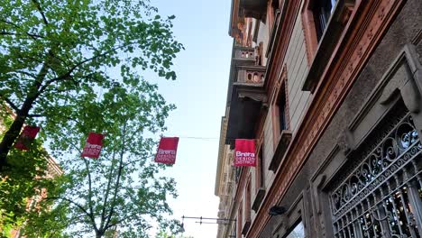 red flags waving between buildings in milan, italy