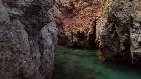 pequeño estanque de agua de mar verde en una cueva de piedra caliza escondida, portugal