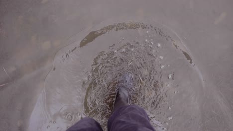 man in wellies walking in muddy puddles in countryside, slow motion point of view
