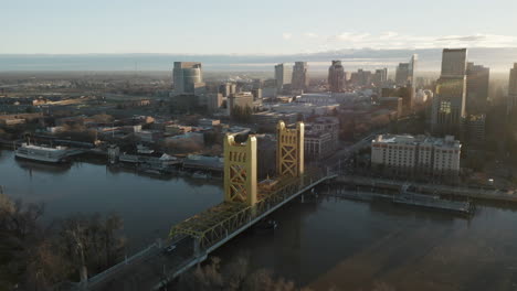 Aerial-drone-right-parallax-of-Tower-Bridge-and-Downtown-Sacramento,-CA,-including-Old-Sacramento---State-Capitol-in-background-during-sunrise