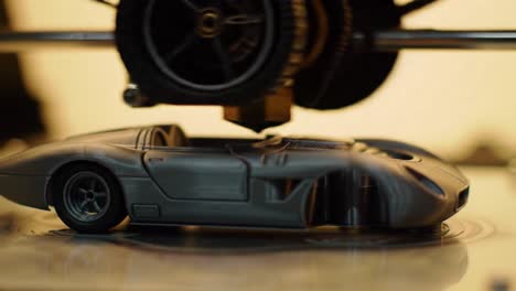 3d printing process: close-up view of a grey car model being printed with precision and detail by advanced technology